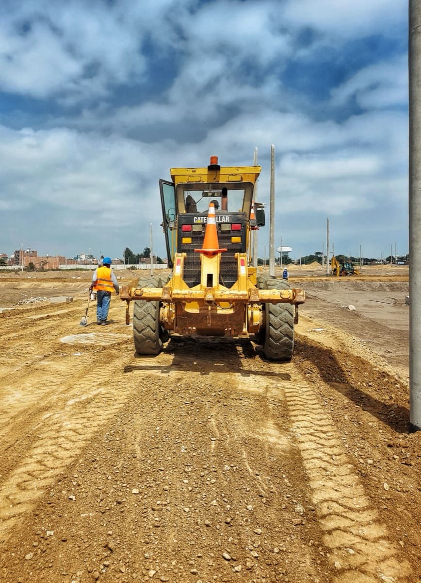 Niveleuse profilant une voie en terre sur un chantier de viabilisation